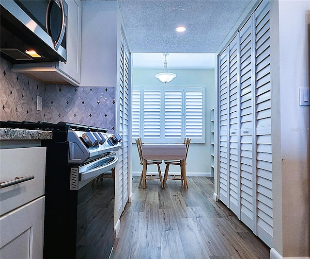 6060 Shore Blvd S Unit 903, Gulfport, FL 33707 - kitchen featuring stainless steel microwave, wood finished floors, backsplash, baseboards, and recessed lighting