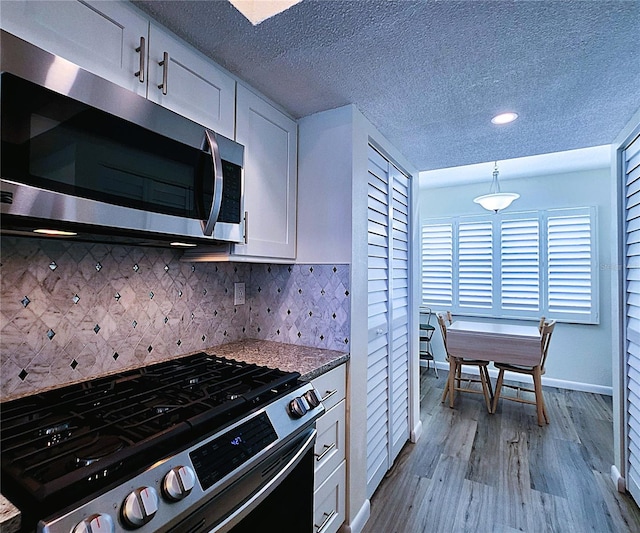 6060 Shore Blvd S Unit 903, Gulfport, FL 33707 - kitchen with appliances with stainless steel finishes, dark wood finished floors, white cabinetry, decorative backsplash, and baseboards