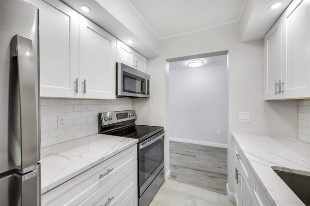 11224 82nd Ave Unit 104, Seminole, FL 33772 - kitchen with stainless steel appliances, white cabinets, decorative backsplash, light stone countertops, and crown molding