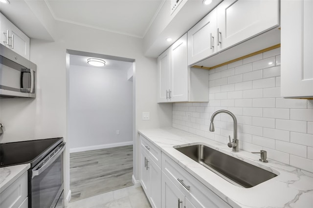 11224 82nd Ave Unit 104, Seminole, FL 33772 - kitchen featuring a sink, appliances with stainless steel finishes, white cabinetry, backsplash, and baseboards