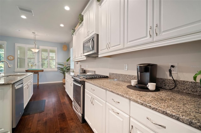 5102 Coastal Scene Dr, Apollo Beach, FL 33572 - kitchen with stainless steel appliances, a sink, white cabinetry, dark wood-style flooring, and light stone counters