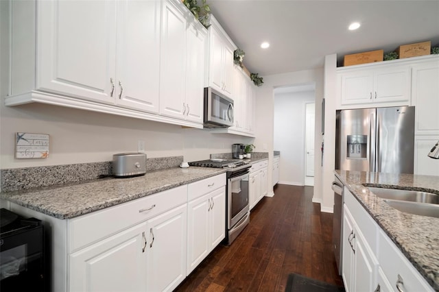 5102 Coastal Scene Dr, Apollo Beach, FL 33572 - kitchen with appliances with stainless steel finishes, a sink, white cabinetry, dark wood-style flooring, and recessed lighting