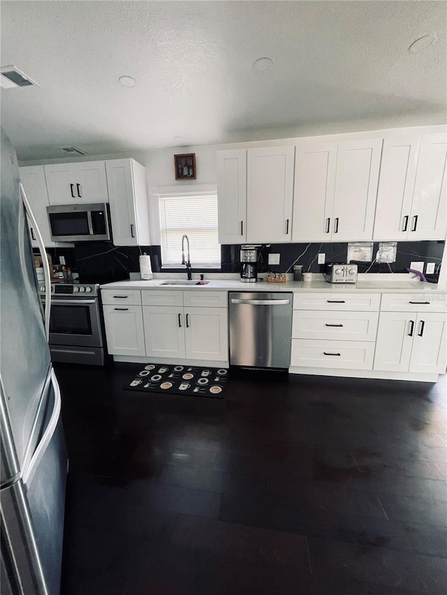 4049 Ponea Dr, Sarasota, FL 34241 - kitchen featuring appliances with stainless steel finishes, a sink, white cabinets, and a textured ceiling