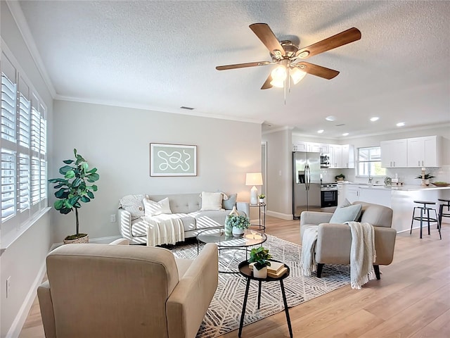 9929 Bay Dr, Gibsonton, FL 33534 - living area featuring crown molding, light wood-style floors, ceiling fan, baseboards, and a textured ceiling