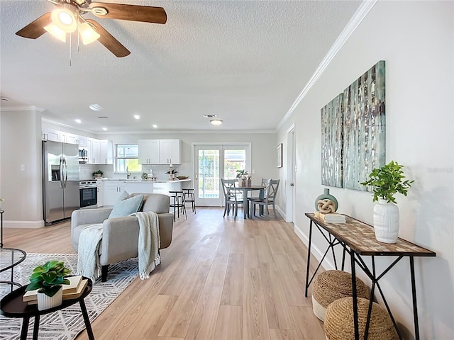 9929 Bay Dr, Gibsonton, FL 33534 - living room featuring light wood-type flooring, ornamental molding, ceiling fan, a textured ceiling, and baseboards