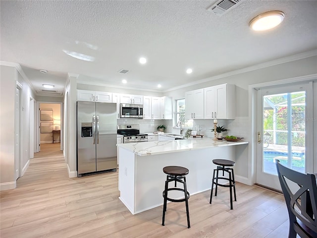 9929 Bay Dr, Gibsonton, FL 33534 - kitchen with stainless steel appliances, a peninsula, ornamental molding, a kitchen bar, and decorative backsplash