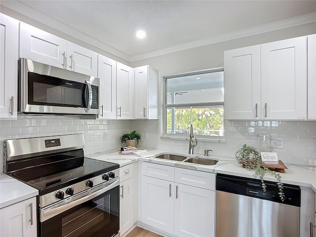 9929 Bay Dr, Gibsonton, FL 33534 - kitchen featuring appliances with stainless steel finishes, a sink, white cabinets, and crown molding