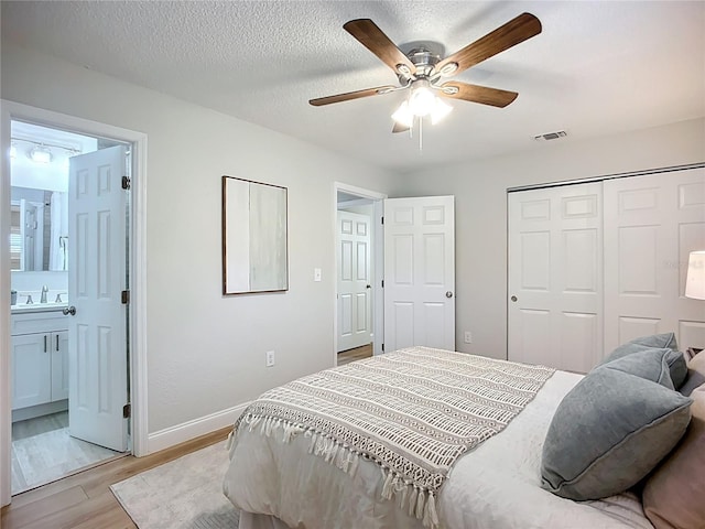 9929 Bay Dr, Gibsonton, FL 33534 - bedroom with light wood-style floors, baseboards, a sink, a closet, and ensuite bathroom