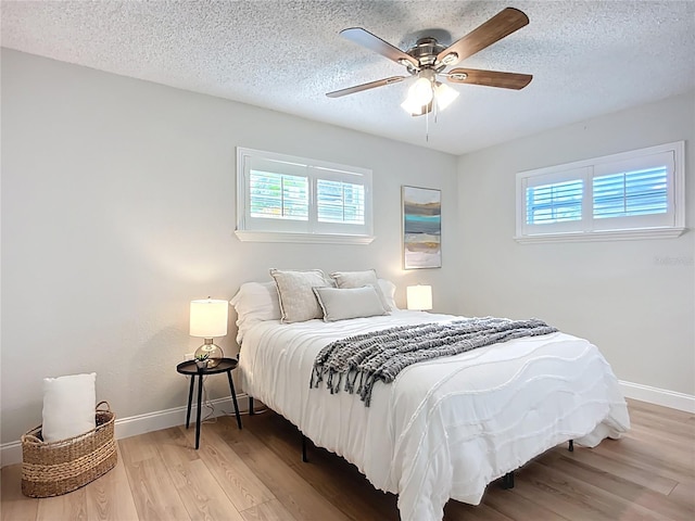 9929 Bay Dr, Gibsonton, FL 33534 - bedroom featuring multiple windows, light wood-style flooring, baseboards, and a textured ceiling