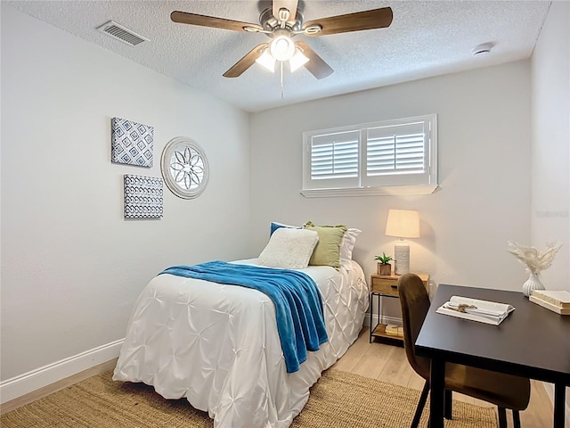 9929 Bay Dr, Gibsonton, FL 33534 - bedroom with a textured ceiling, light wood-type flooring, baseboards, and a ceiling fan