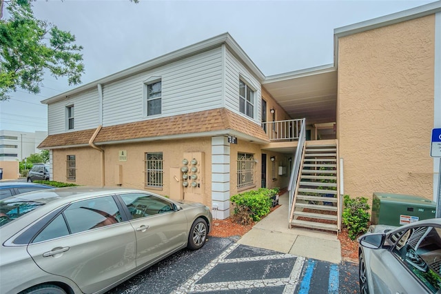 4708 Michael Ct Unit 103, Tampa, FL 33614 - view of side of home with roof with shingles, uncovered parking, stairs, and stucco siding