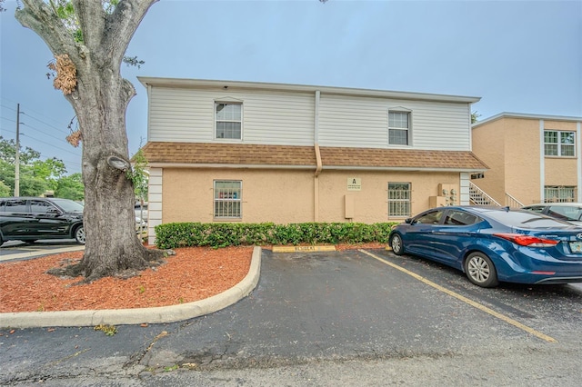 4708 Michael Ct Unit 103, Tampa, FL 33614 - view of front of home with uncovered parking, roof with shingles, and stucco siding