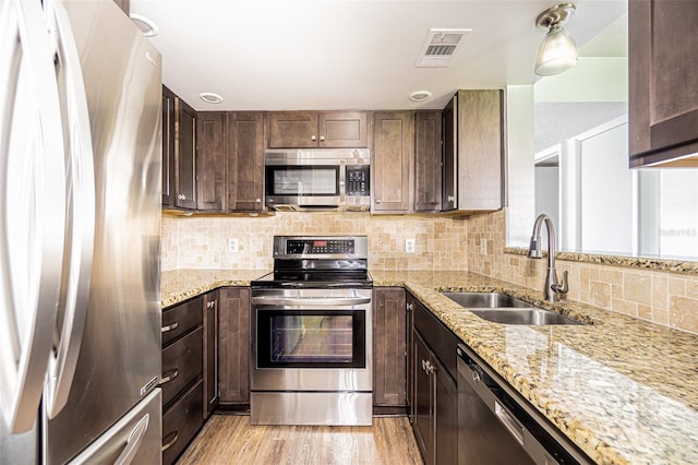 4708 Michael Ct Unit 103, Tampa, FL 33614 - kitchen with stainless steel appliances, a sink, dark brown cabinetry, light wood-style flooring, and tasteful backsplash