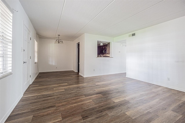 4708 Michael Ct Unit 103, Tampa, FL 33614 - empty room with a chandelier, dark wood-style floors, baseboards, and a textured ceiling
