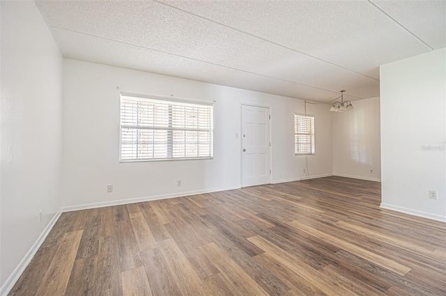 4708 Michael Ct Unit 103, Tampa, FL 33614 - empty room featuring a chandelier, wood finished floors, a textured ceiling, and baseboards