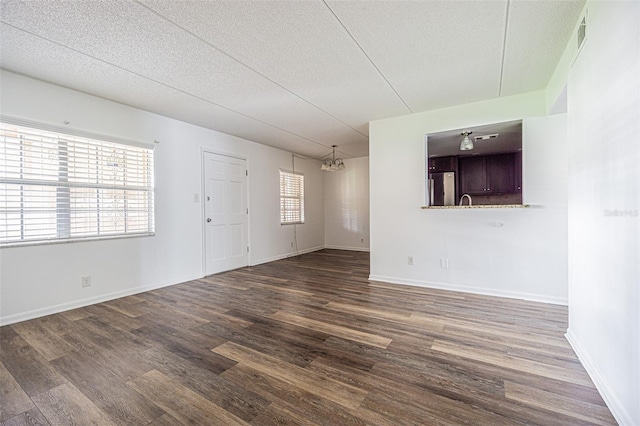 4708 Michael Ct Unit 103, Tampa, FL 33614 - empty room with dark wood-style flooring, a textured ceiling, a chandelier, and baseboards