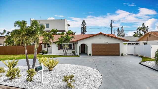 7125 S Shore Dr S, Saint Petersburg, FL 33707 - view of front of house featuring curved driveway, an attached garage, a tiled roof, and stucco siding