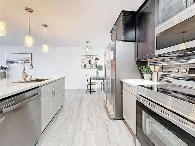 7125 S Shore Dr S, Saint Petersburg, FL 33707 - kitchen with stainless steel appliances, a sink, decorative light fixtures, light wood-style floors, and tasteful backsplash
