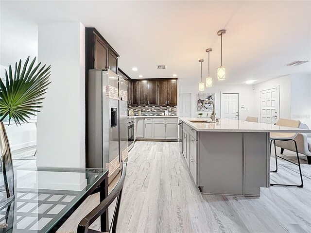 7125 S Shore Dr S, Saint Petersburg, FL 33707 - kitchen with a sink, light wood-style flooring, light countertops, decorative backsplash, and dark brown cabinets