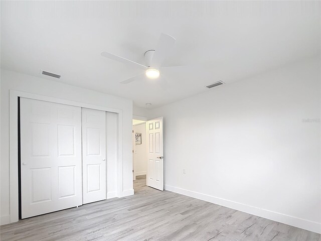 7125 S Shore Dr S, Saint Petersburg, FL 33707 - unfurnished bedroom featuring a closet, baseboards, light wood finished floors, and ceiling fan