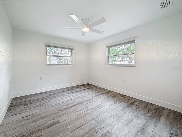 7125 S Shore Dr S, Saint Petersburg, FL 33707 - spare room featuring plenty of natural light, wood finished floors, a ceiling fan, and baseboards