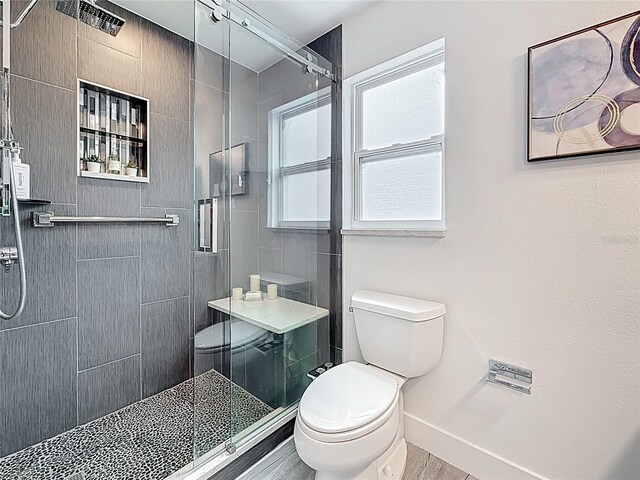 7125 S Shore Dr S, Saint Petersburg, FL 33707 - bathroom with toilet, a stall shower, baseboards, and wood finished floors
