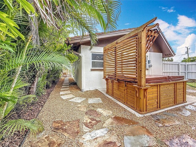 7125 S Shore Dr S, Saint Petersburg, FL 33707 - view of side of home with a hot tub and stucco siding