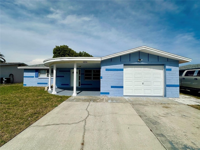 4836 Daphne St, New Port Richey, FL 34652 - view of front of property with a front lawn, a garage, concrete driveway, a porch, and brick siding