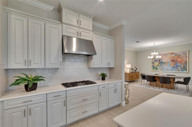 4795 Freccia Loop, Wesley Chapel, FL 33543 - kitchen with under cabinet range hood, gas stovetop, a chandelier, ornamental molding, and light countertops