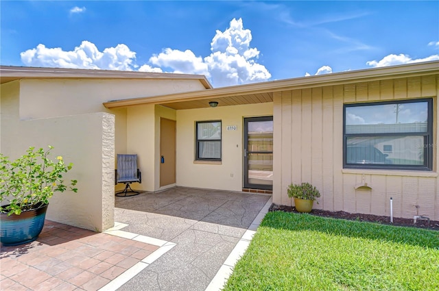6550 Teak Ct, Zephyrhills, FL 33542 - view of exterior entry with a patio, a yard, and stucco siding
