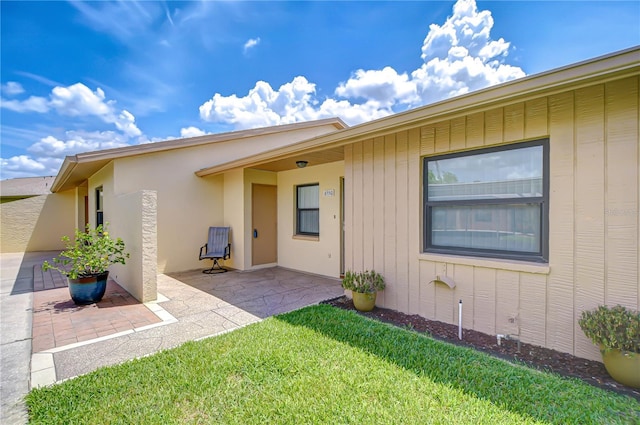 6550 Teak Ct, Zephyrhills, FL 33542 - property entrance with a patio area, a lawn, and stucco siding