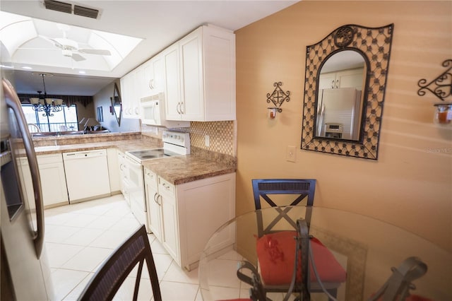 1846 Golfview Dr Unit 1846, Tarpon Springs, FL 34689 - kitchen with white appliances, a skylight, light tile patterned floors, white cabinets, and a chandelier