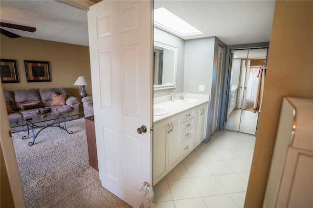 1846 Golfview Dr Unit 1846, Tarpon Springs, FL 34689 - bathroom with double vanity, a textured ceiling, a skylight, ceiling fan, and tile patterned floors