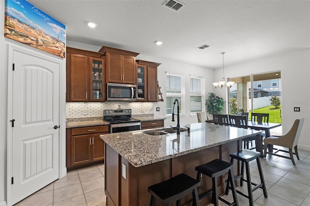 2296 Crossbow St, Clermont, FL 34715 - kitchen featuring appliances with stainless steel finishes, a sink, a chandelier, light tile patterned floors, and light stone counters