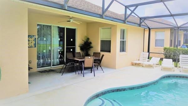 189 Minniehaha Cir, Haines City, FL 33844 - outdoor pool featuring a patio, ceiling fan, glass enclosure, and outdoor dining area