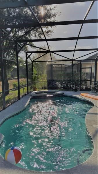 189 Minniehaha Cir, Haines City, FL 33844 - view of swimming pool with glass enclosure, a patio area, and a pool with connected hot tub