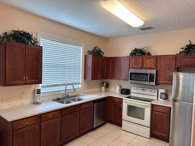189 Minniehaha Cir, Haines City, FL 33844 - kitchen featuring stainless steel appliances, a sink, light countertops, a textured ceiling, and light tile patterned floors