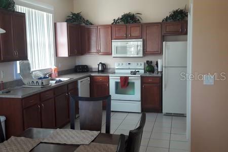 189 Minniehaha Cir, Haines City, FL 33844 - kitchen with white appliances, light tile patterned floors, a sink, and light countertops