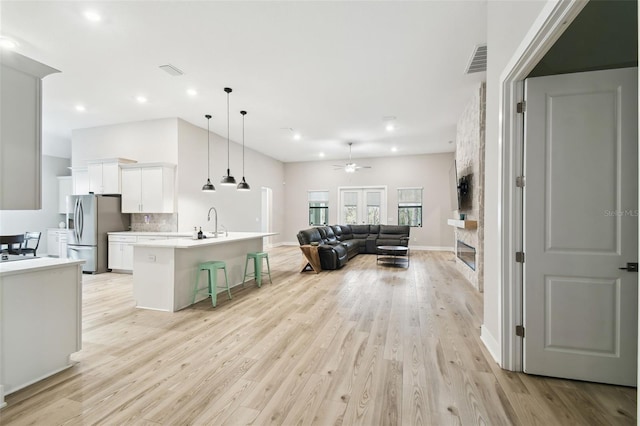 13334 Oldenburg Dr, Hudson, FL 34667 - kitchen featuring stainless steel refrigerator with ice dispenser, open floor plan, a kitchen breakfast bar, a ceiling fan, and white cabinets
