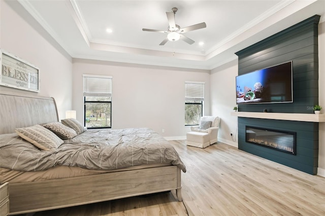 13334 Oldenburg Dr, Hudson, FL 34667 - bedroom with wood finished floors, a raised ceiling, a large fireplace, baseboards, and crown molding