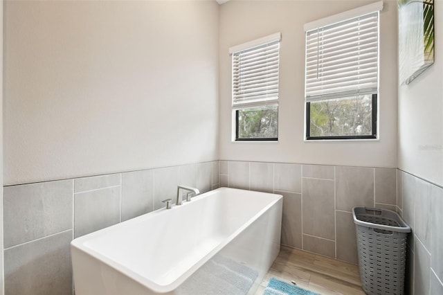 13334 Oldenburg Dr, Hudson, FL 34667 - bathroom with tile walls, a freestanding tub, wood finished floors, and a wainscoted wall