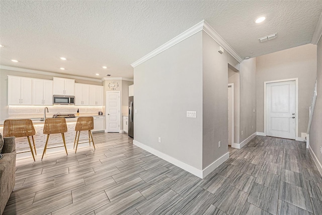 8719 Winning Fields Rd, New Port Richey, FL 34655 - kitchen featuring stainless steel appliances, open floor plan, white cabinetry, ornamental molding, and baseboards