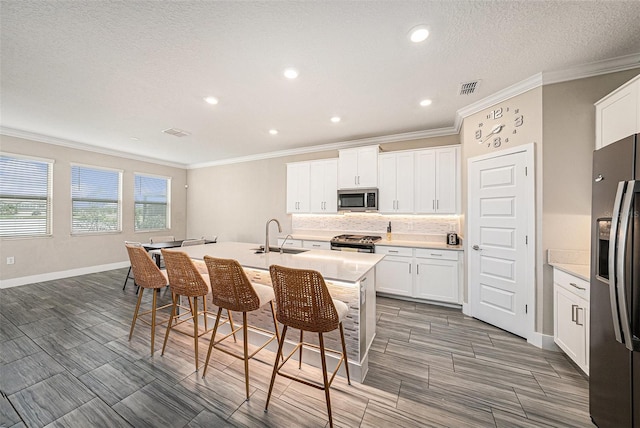 8719 Winning Fields Rd, New Port Richey, FL 34655 - kitchen with appliances with stainless steel finishes, a sink, ornamental molding, an island with sink, and tasteful backsplash