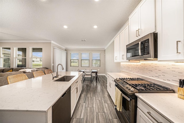 8719 Winning Fields Rd, New Port Richey, FL 34655 - kitchen with appliances with stainless steel finishes, a sink, ornamental molding, white cabinetry, and tasteful backsplash
