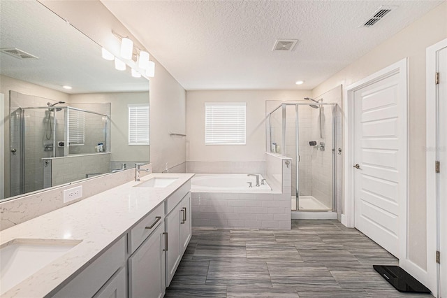 8719 Winning Fields Rd, New Port Richey, FL 34655 - bathroom with a bath, a shower stall, double vanity, a textured ceiling, and recessed lighting