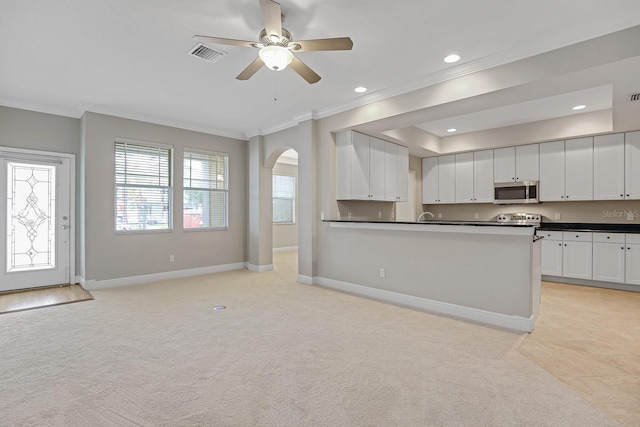 16137 Churchview Dr, Lithia, FL 33547 - kitchen featuring stainless steel microwave, crown molding, dark countertops, arched walkways, and light carpet