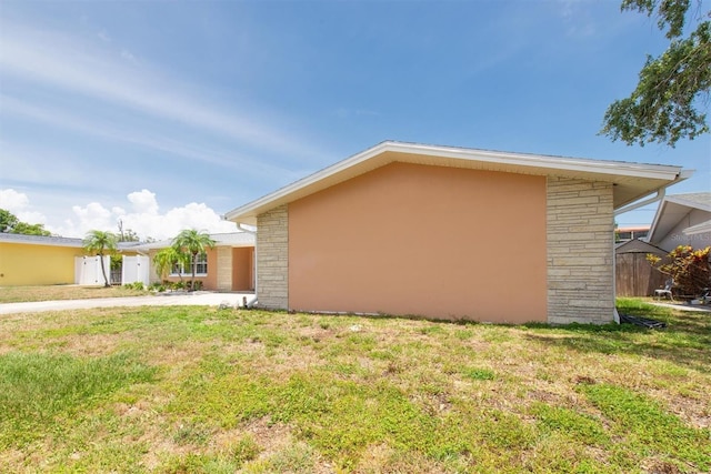 9591 Commodore Dr, Seminole, FL 33776 - view of side of home featuring a lawn and stucco siding