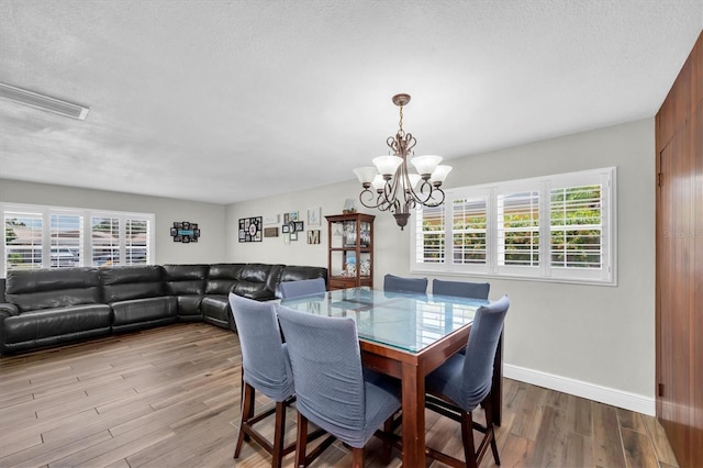 9591 Commodore Dr, Seminole, FL 33776 - dining room featuring a chandelier, wood finished floors, healthy amount of natural light, baseboards, and a textured ceiling