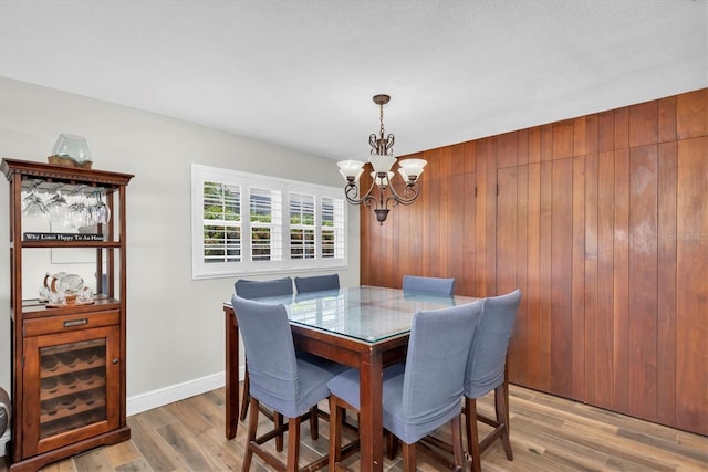 9591 Commodore Dr, Seminole, FL 33776 - dining room featuring a chandelier, wood walls, and light wood-type flooring