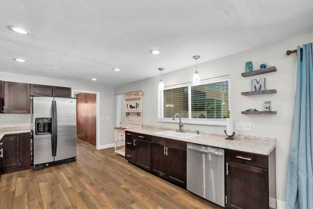 9591 Commodore Dr, Seminole, FL 33776 - kitchen with stainless steel appliances, a sink, dark brown cabinetry, wood finished floors, and baseboards